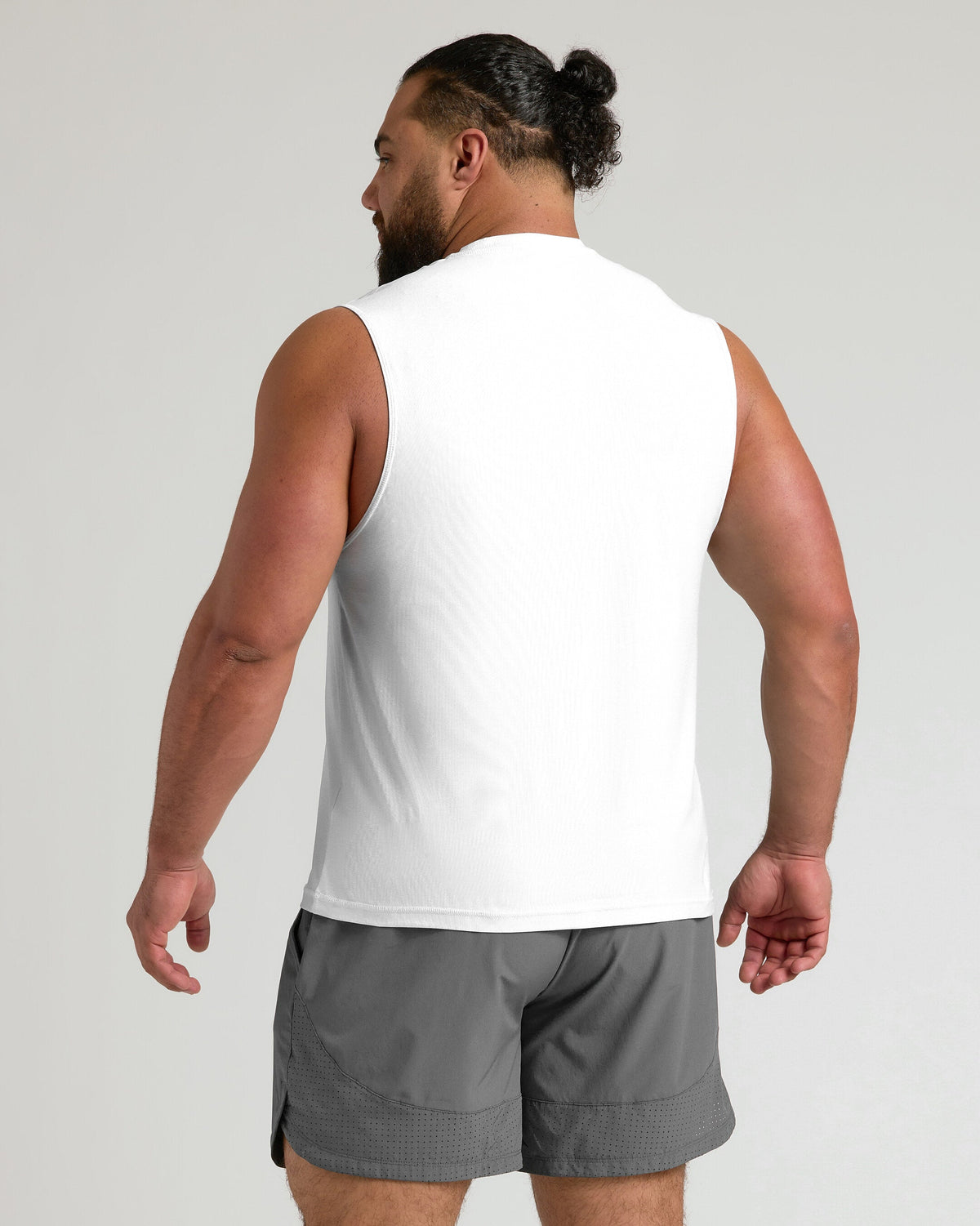 Man in White Sleeveless Active Muscle Tee, gray shorts, workout-ready.