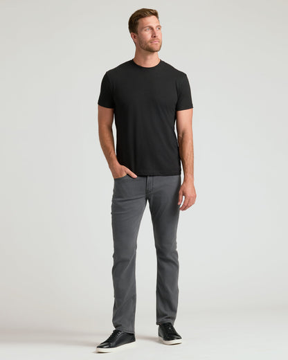 Black crew neck t-shirt with short sleeves, paired with gray jeans and black sneakers.
