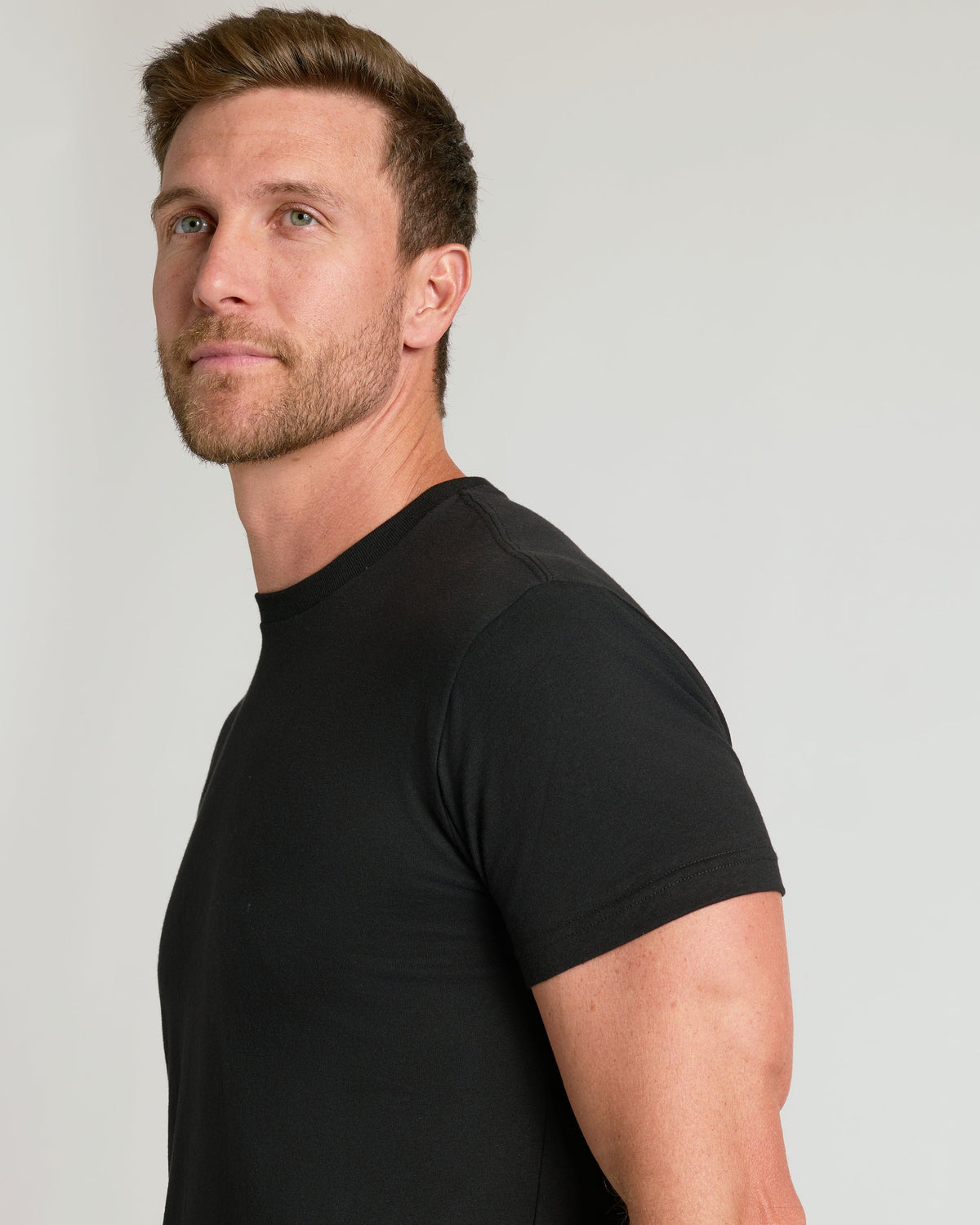 Black short-sleeve crew neck t-shirt on male model, side view.