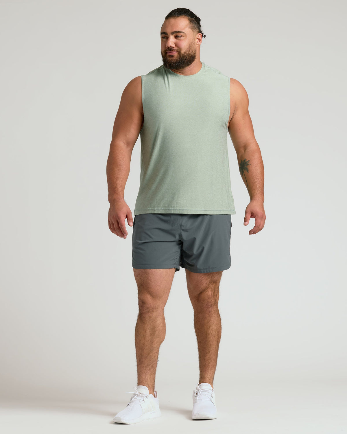 Man wearing Lichen Sleeveless Active Muscle Tee, athletic shorts, and running shoes.