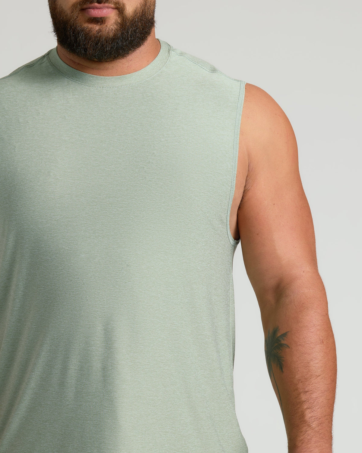 Lichen Sleeveless Active Muscle Tee on man with palm-tree tattoo.